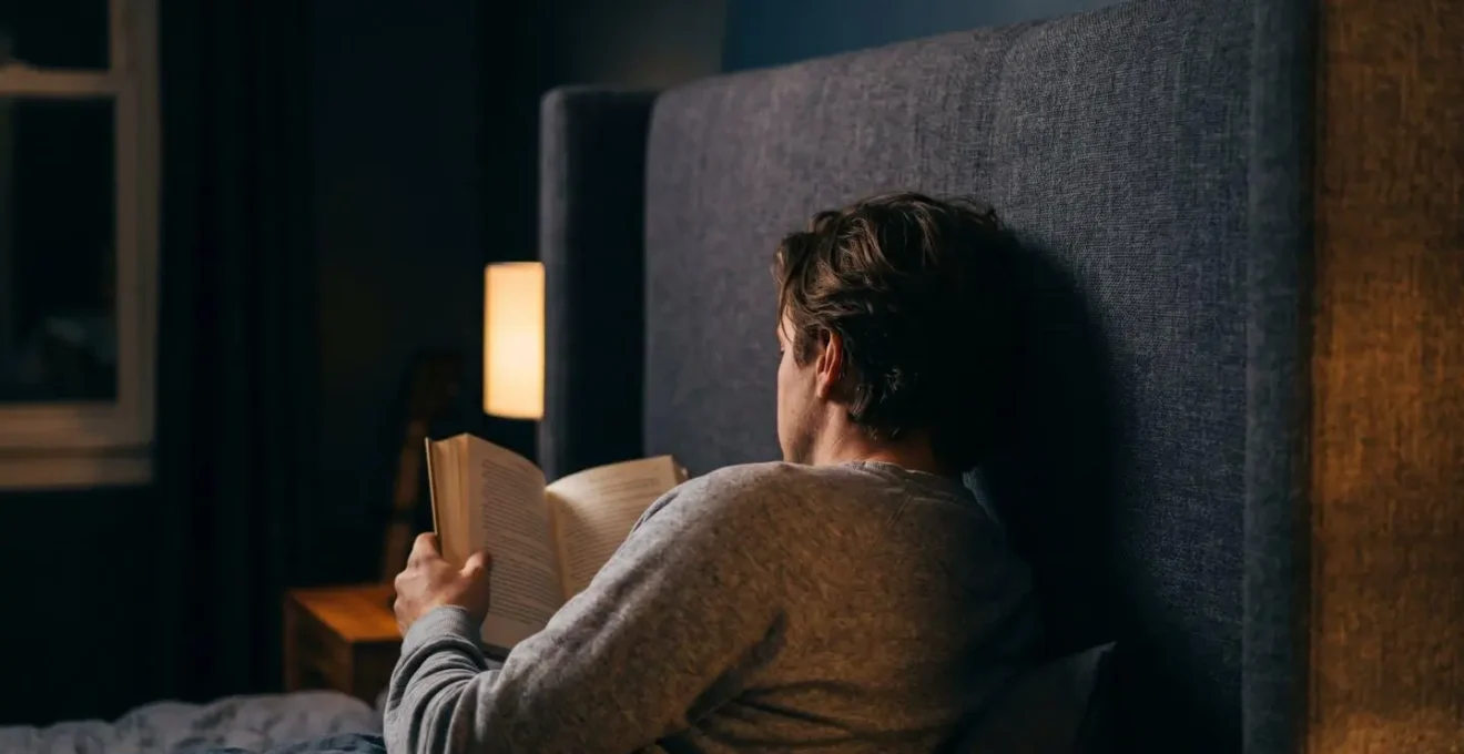 Cabecero alto actuando como barrera visual contra luz residual en dormitorio oscuro con ambiente de descanso óptimo