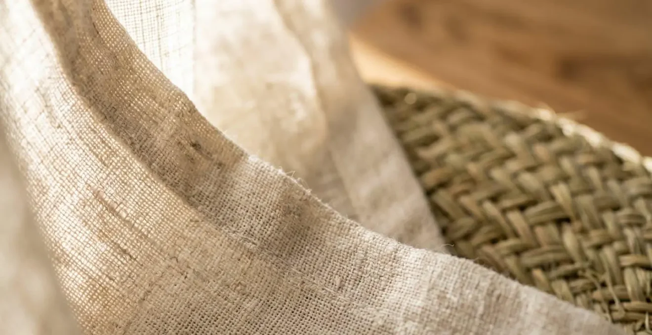 Detalle macro de textiles naturales nórdicos adaptados al clima mediterráneo, lino y fibras vegetales con luz filtrada
